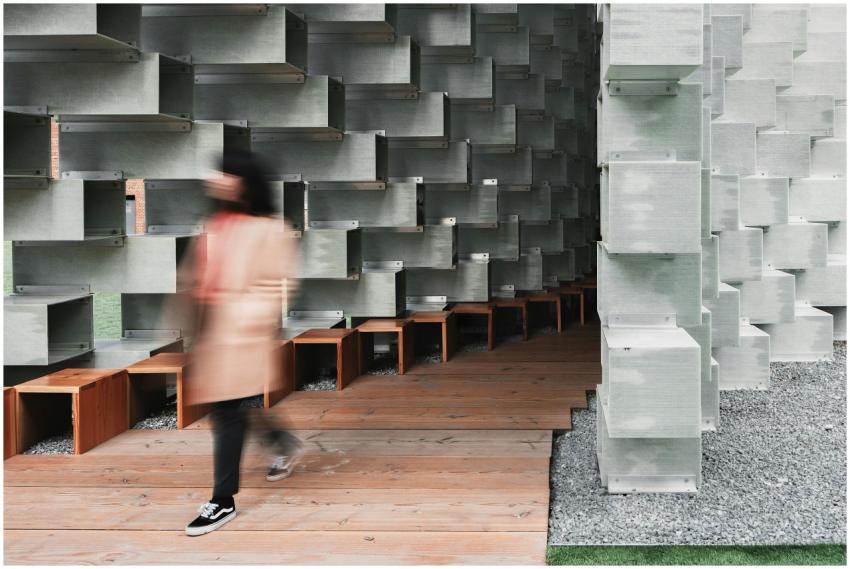 A blurred figure walks by a modern architectural i