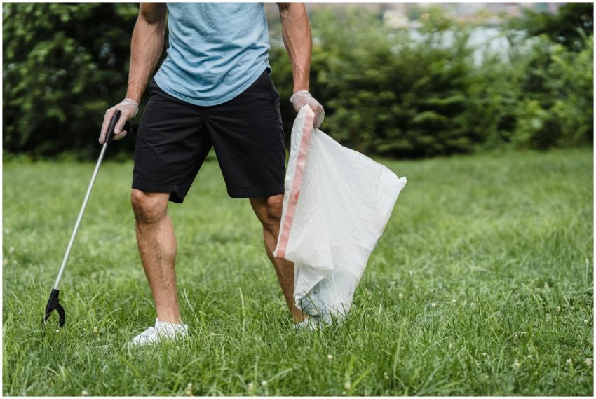 A volunteer cleaning a park, holding a grabber and