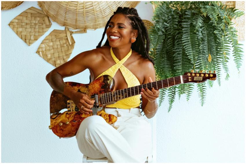 Smiling woman with braided hair playing guitar in