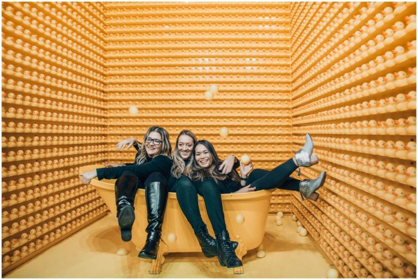 Three women having fun in a bathtub surrounded by