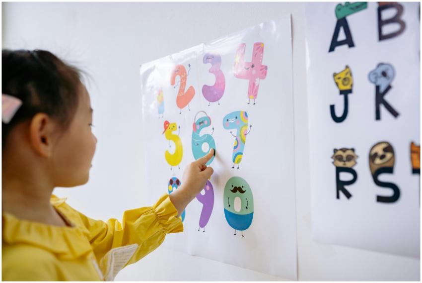 A young girl in a yellow shirt learning numbers in