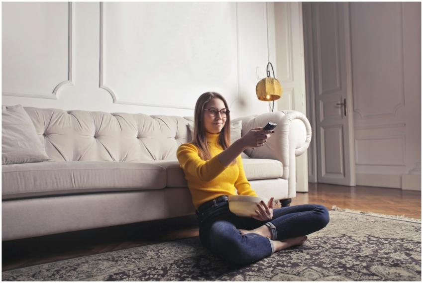 Smiling young woman in a yellow sweater watching T