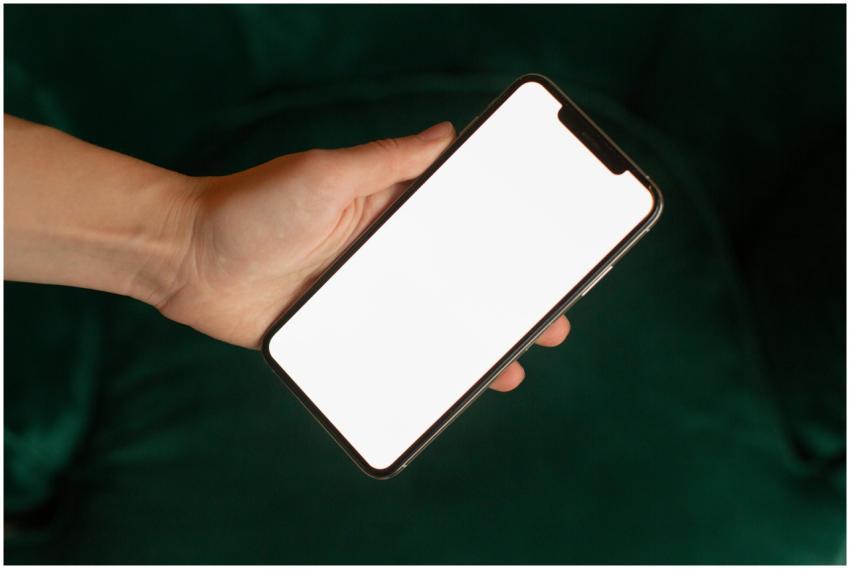 Hand holding a smartphone with a blank screen for