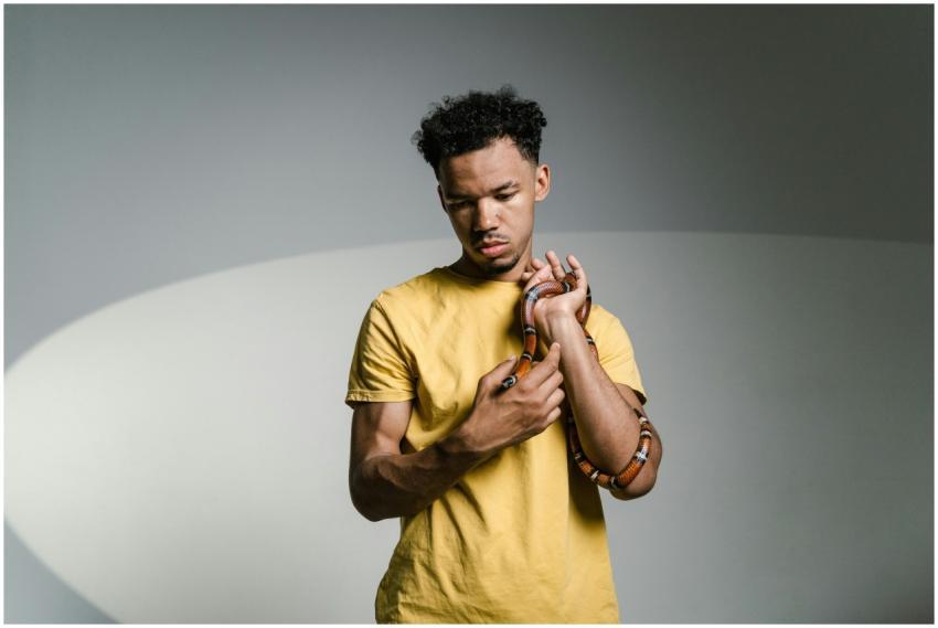 A young man holds a snake, overcoming ophidiophobi