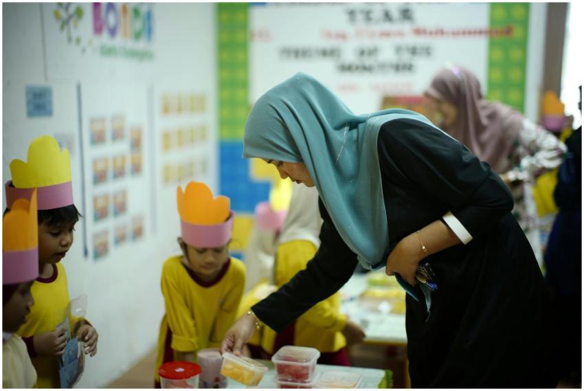 A teacher guides young students in a classroom act