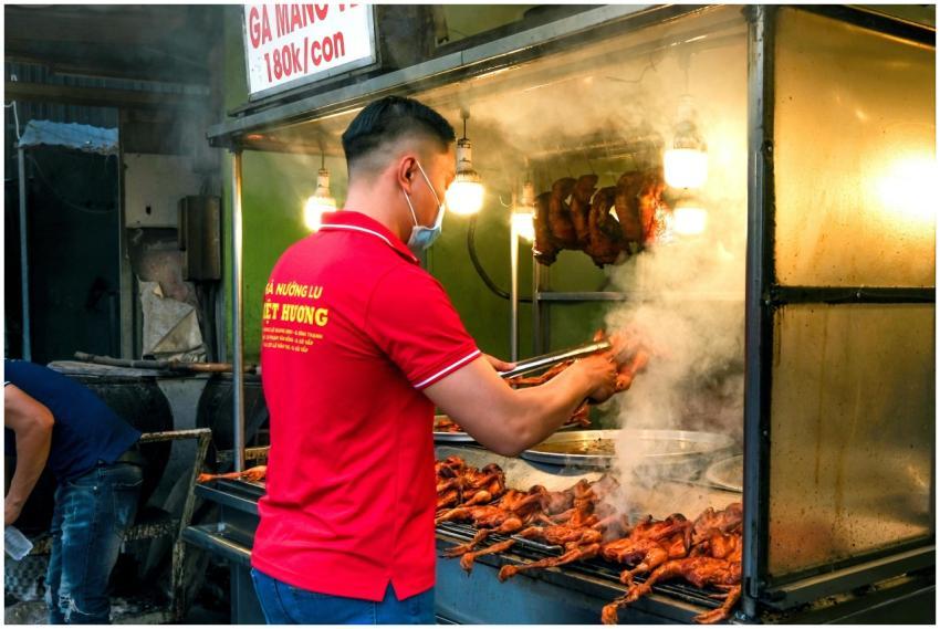 Street vendor grilling chicken at a vibrant market