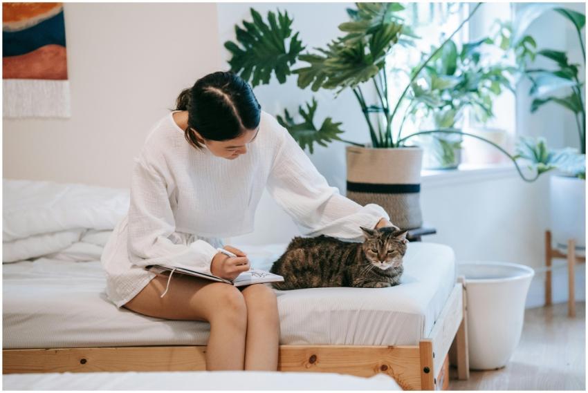An Asian woman in a white outfit journaling while