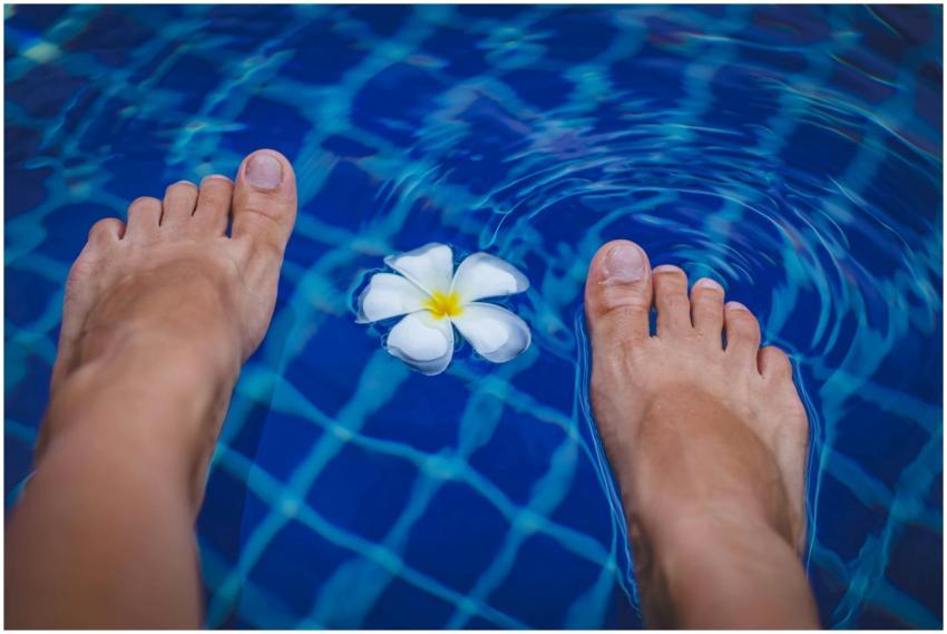 Close-up of feet in a clear blue swimming pool wit