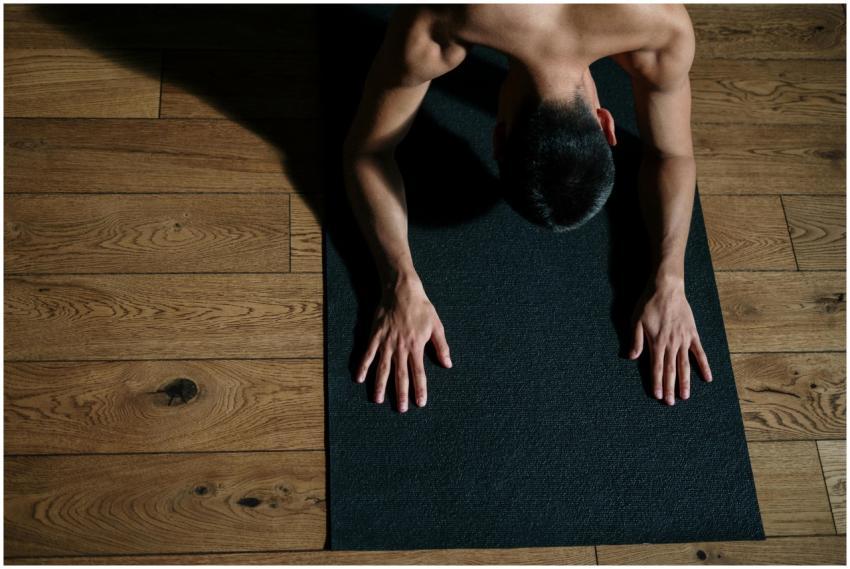 Adult male performing yoga on a mat, emphasizing f