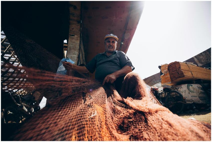 Fisherman repairing nets under the sun in Damietta
