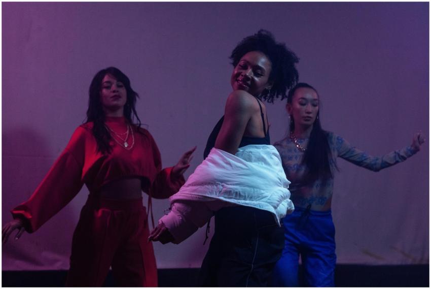 Three female dancers perform dynamically against a