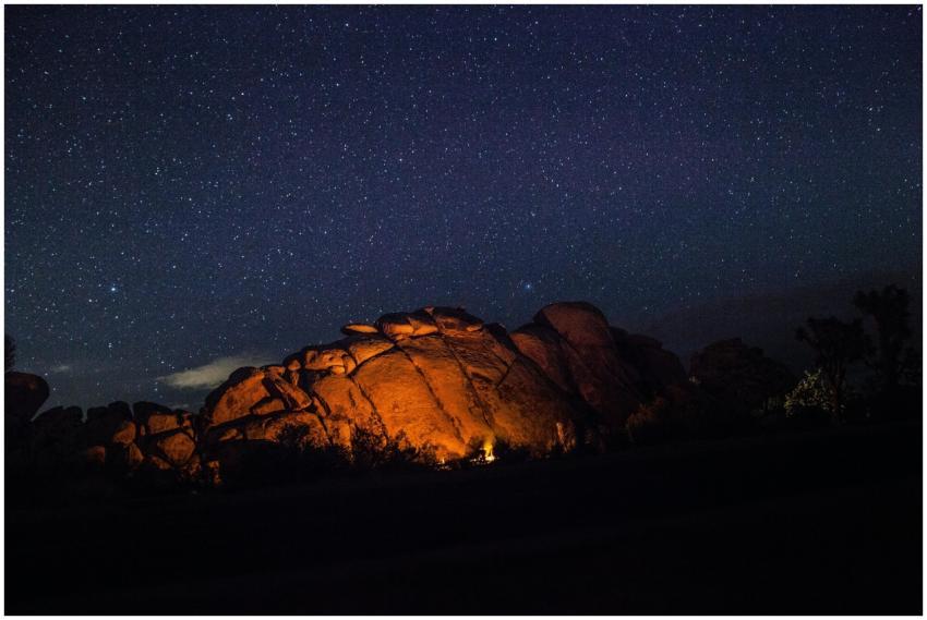 A campfire casts a warm glow on rocky formations u