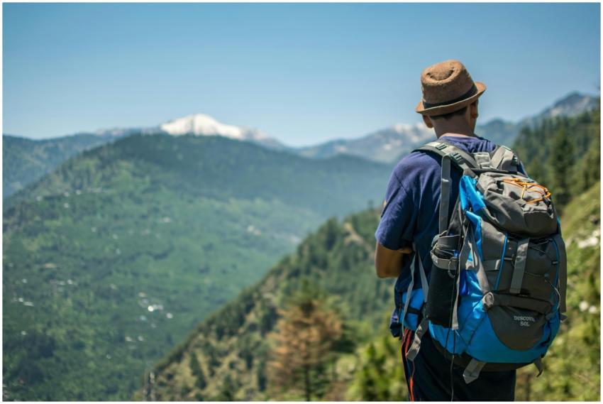 Man with backpack hiking among green mountains und