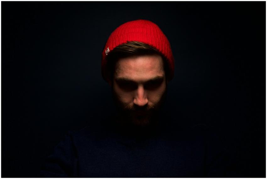 Dramatic low-key portrait of a man in a red beanie
