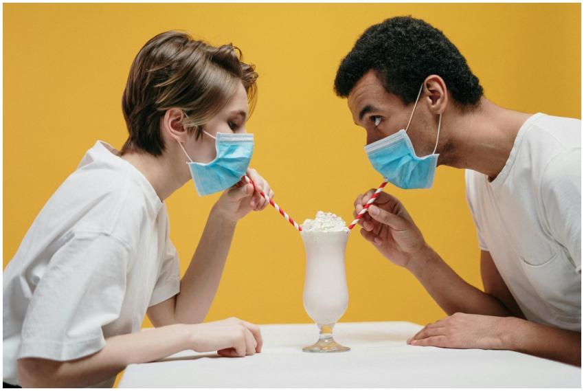 A couple wearing masks humorously shares a milksha