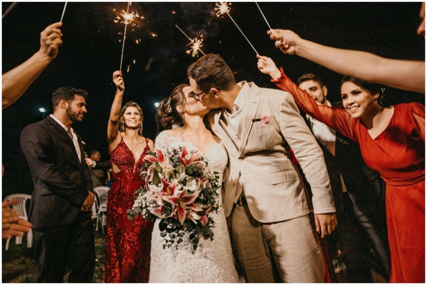 A joyful couple kisses under sparklers, surrounded