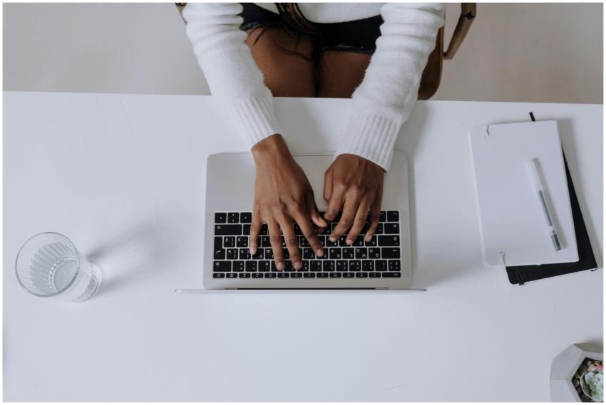 Overhead shot of a woman typing on a laptop in a m