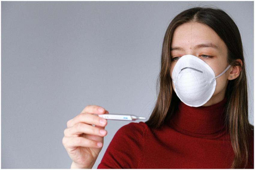 A young woman wearing a mask checks her temperatur