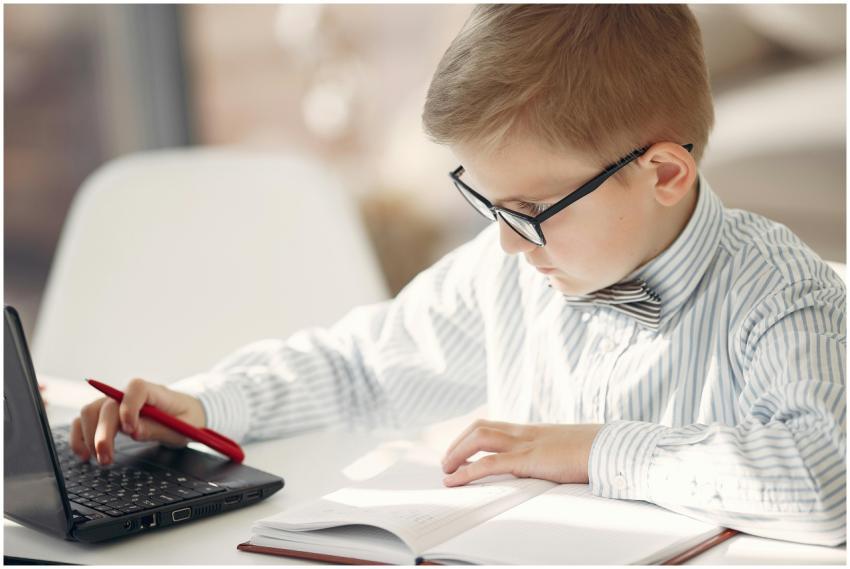 A young boy in glasses and bow tie diligently stud