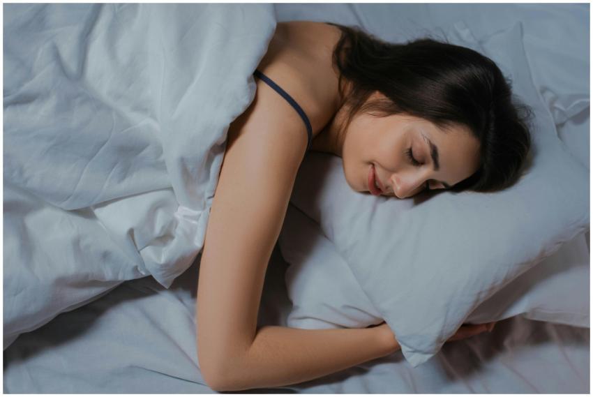 Serene young woman sleeping in cozy bed with white