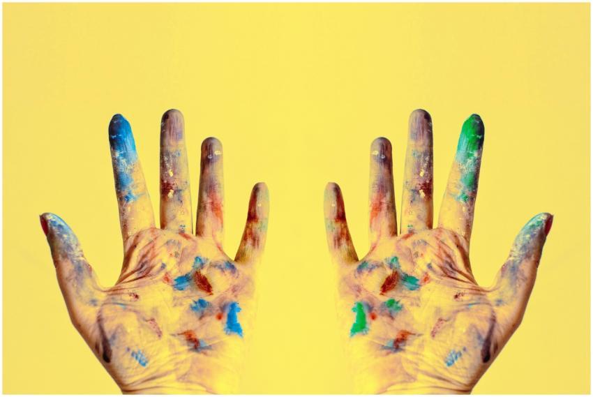 Colorful fingers spread against a bright yellow ba