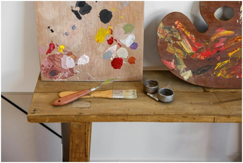 An artist's palette and brushes on a rustic wooden
