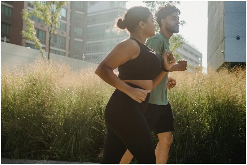 Two adults jogging in an urban park surrounded by