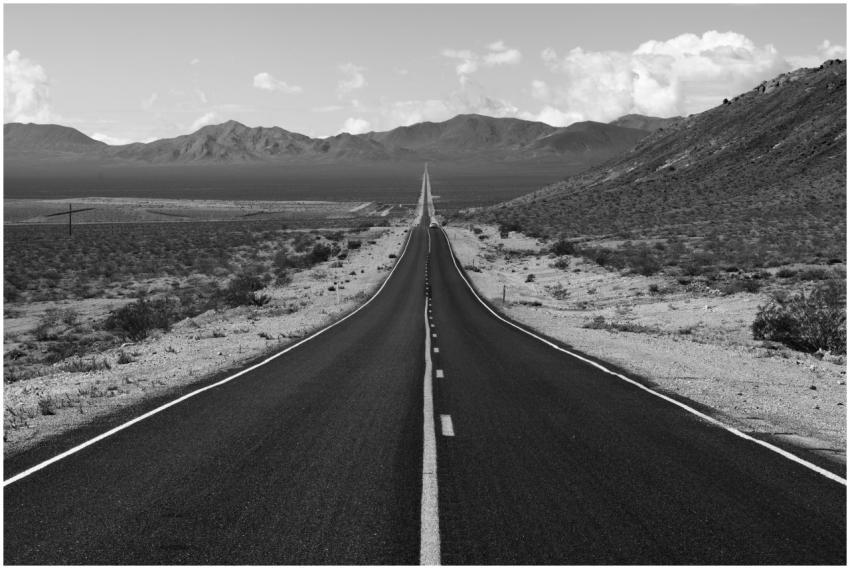 Black and white view of a long, empty highway stre