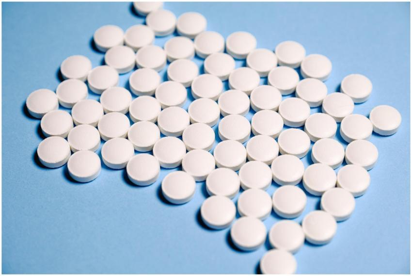 Close-up of white pills on a blue surface represen