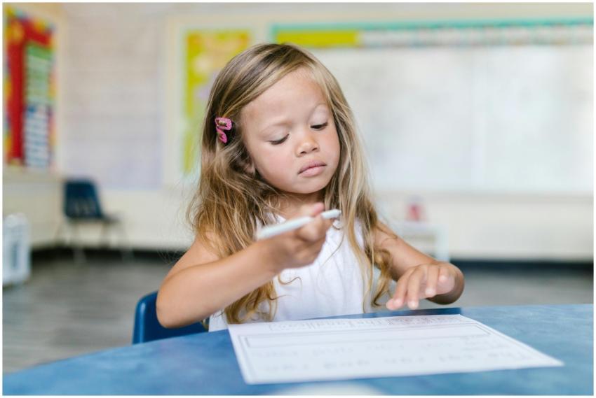A young girl attentively writing in a classroom, c