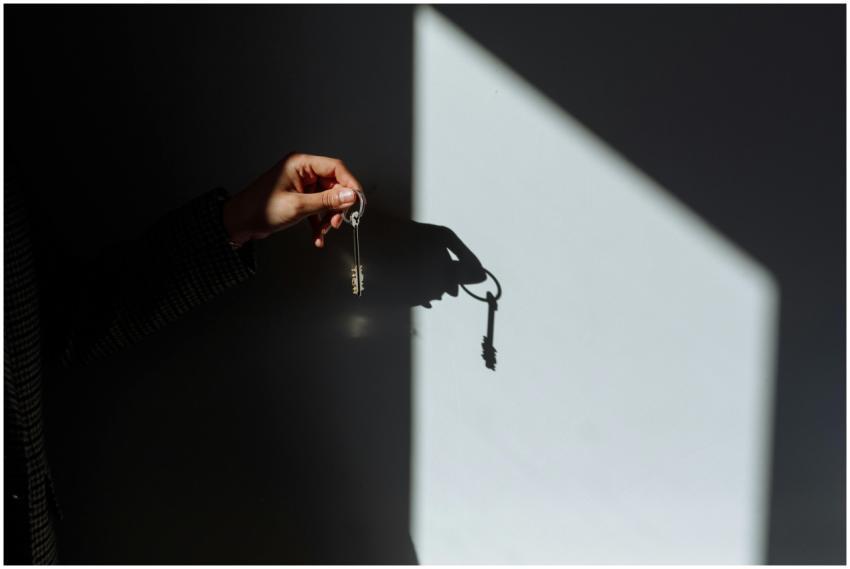 Minimalist photo of a hand holding a key casting a