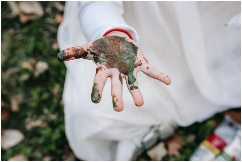 A child's hand covered in paint during outdoor pla