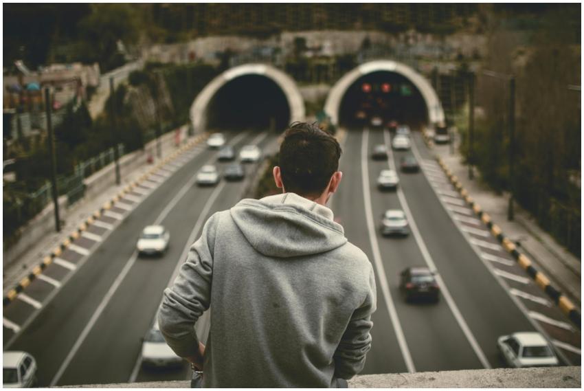 A man in a hoodie looks over traffic entering tunn