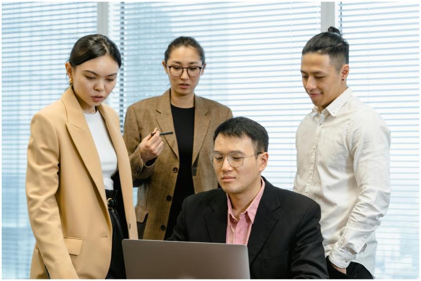 Group of professionals gathered around a laptop fo