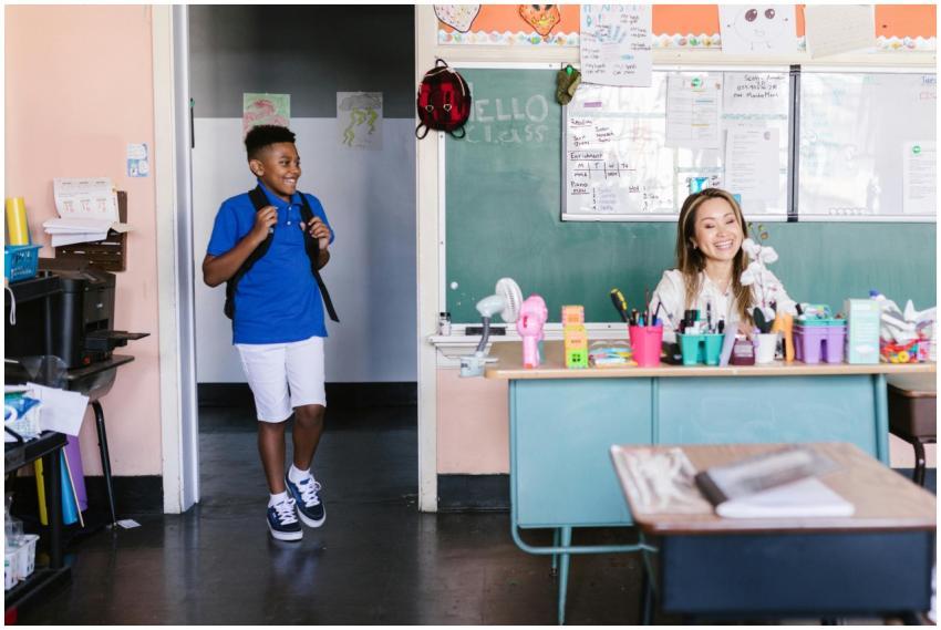 A cheerful student enters the classroom where a te