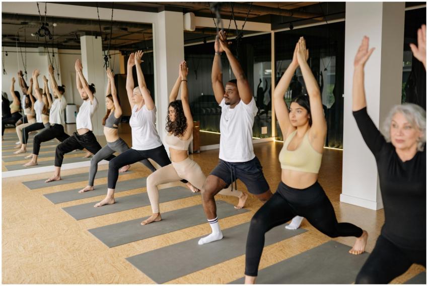 A diverse group practicing yoga with raised arms i