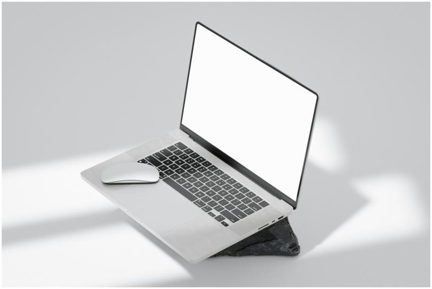 A laptop and wireless mouse on a rock surface with