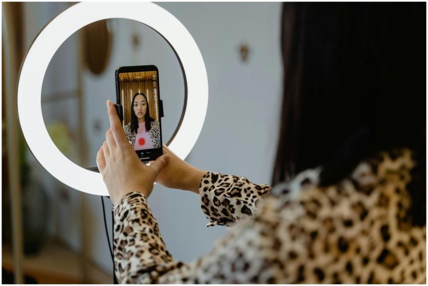 An Asian woman uses a smartphone and ring light fo