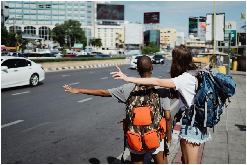 Two travelers with backpacks raising their arms at