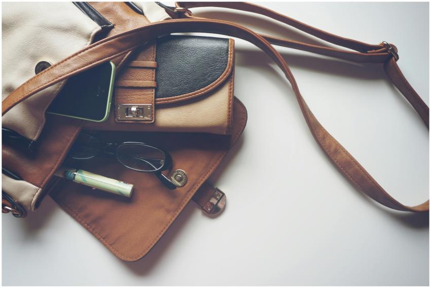 Overhead view of leather bag with eyeglasses, wall