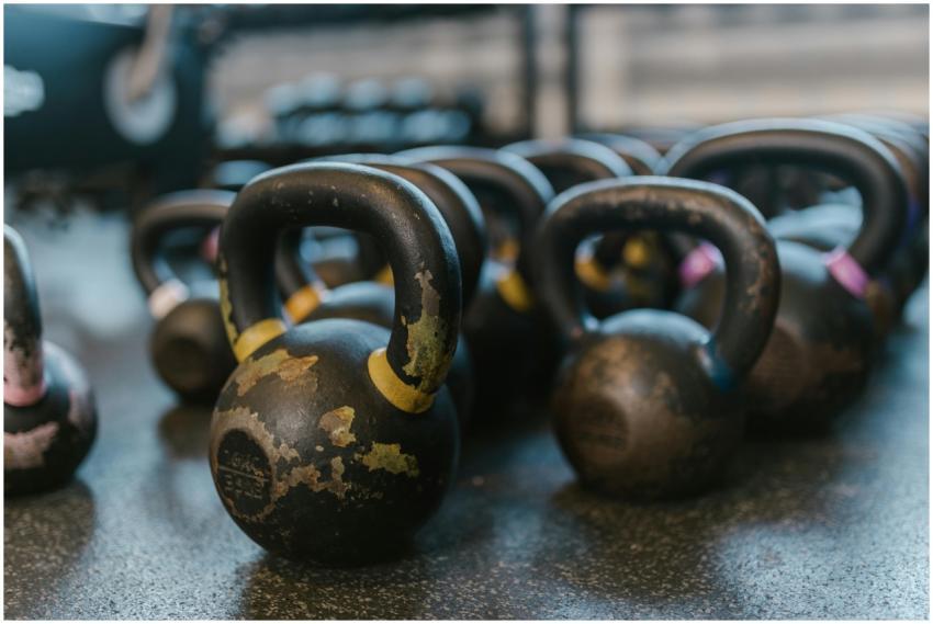 A collection of black kettlebells on a textured gy