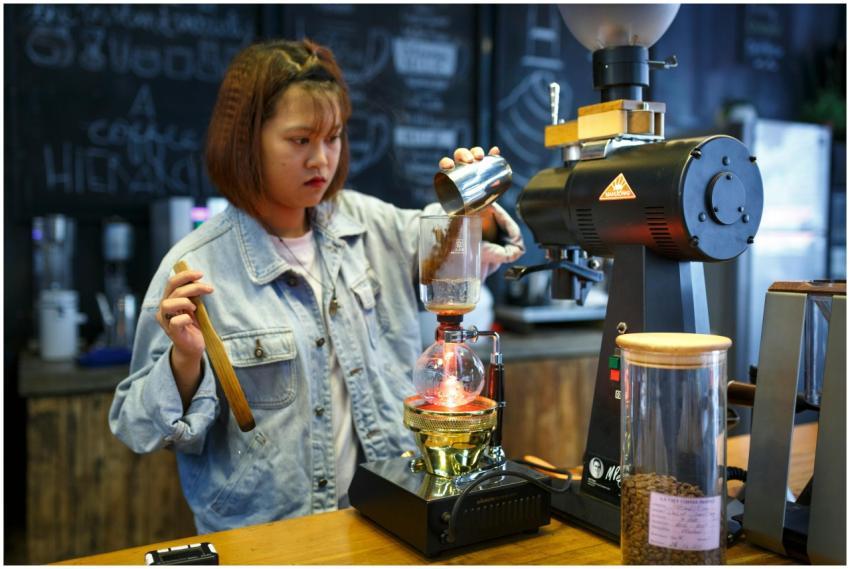 Barista using a coffee siphon in a cozy cafe setti
