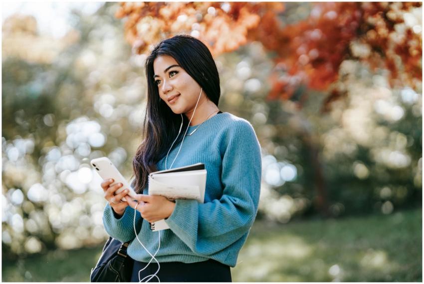 Cheerful young woman outdoors, using phone and ear