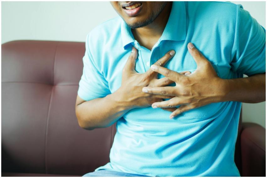 A close-up image of a man clutching his chest, ind