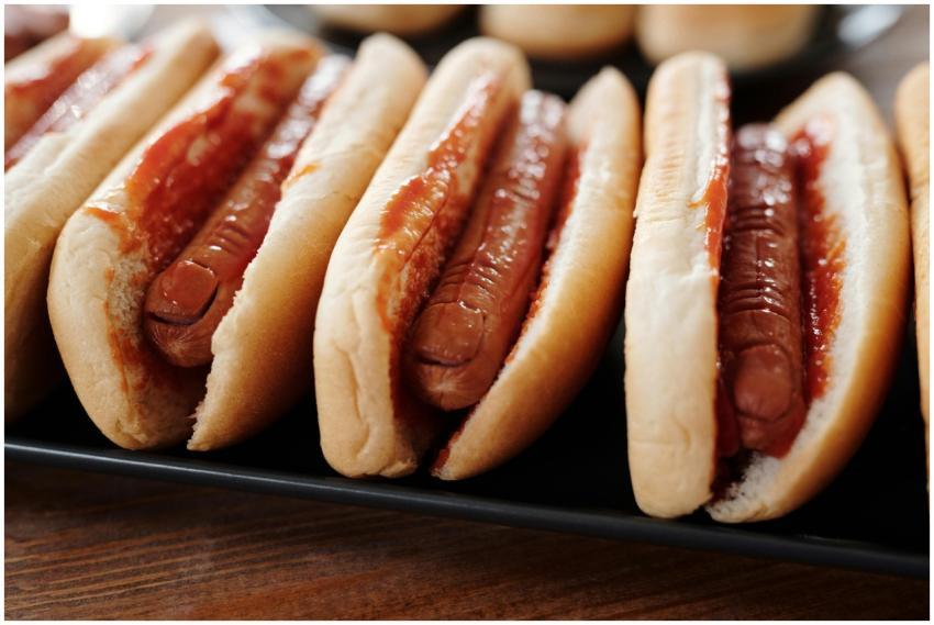 Row of hot dogs topped with ketchup, showcasing a