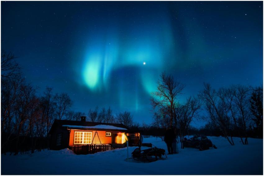 Cabin illuminated under a stunning aurora borealis