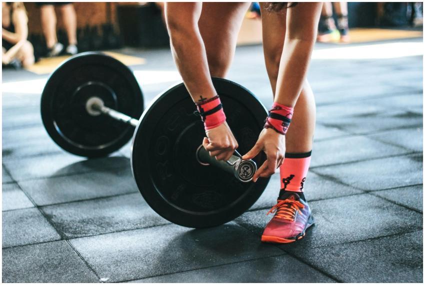 Athlete tightening barbell plates in a gym, emphas
