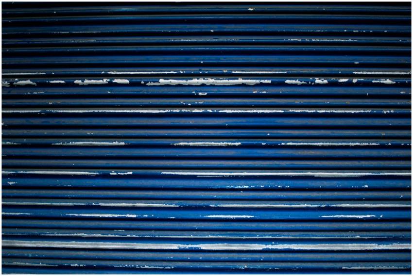 A detailed view of a blue metal shutter with peeli