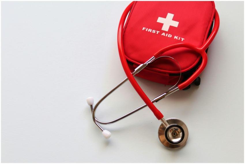 A red first aid kit paired with a stethoscope, sig