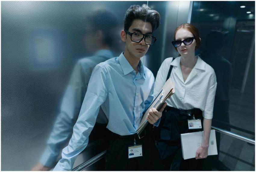 Two serious professionals standing inside an eleva